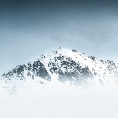 A snow covered mountain top seen through clouds