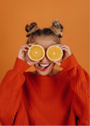 Sophie holding orange slices over her eyes.