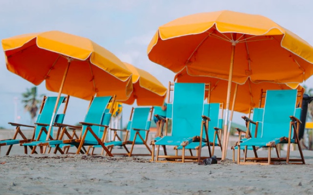 Chairs on the beach with umbrellas over top of them.