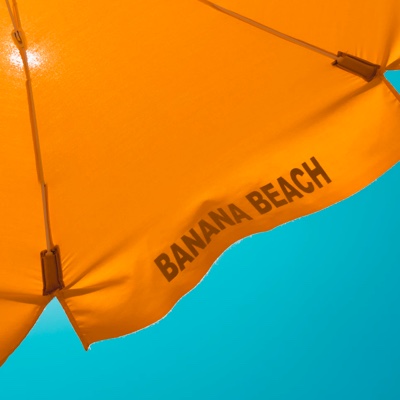 Umbrella top with the words Banana Beach written on it.